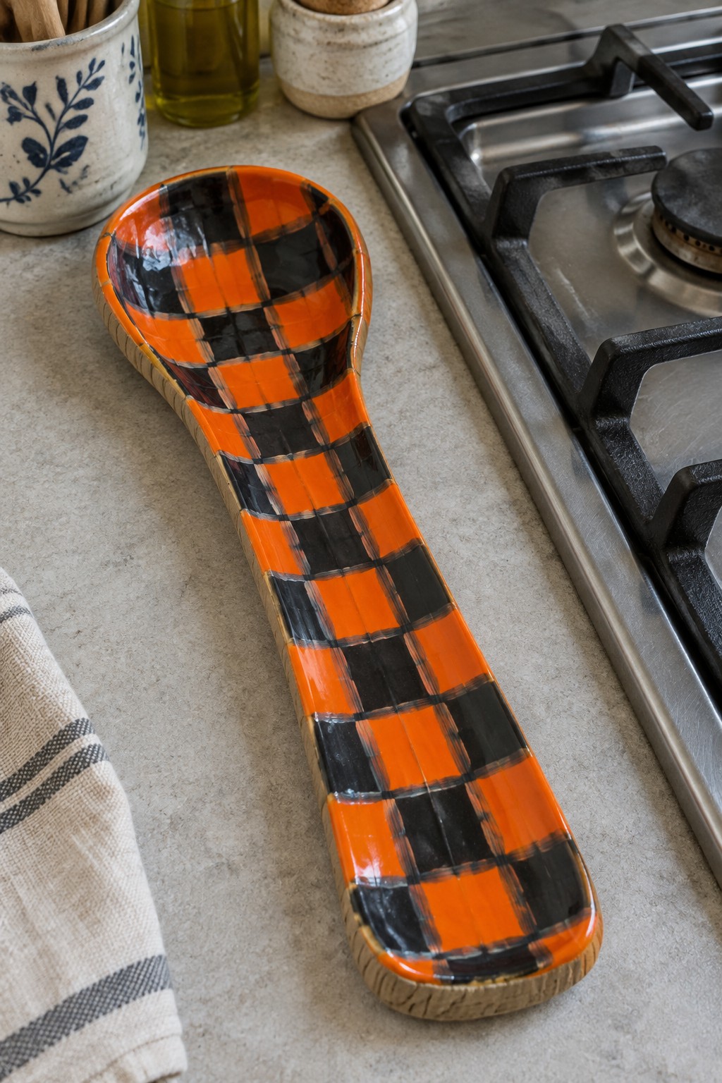 Orange and black plaid ceramic spoon rest on kitchen counter by stove
