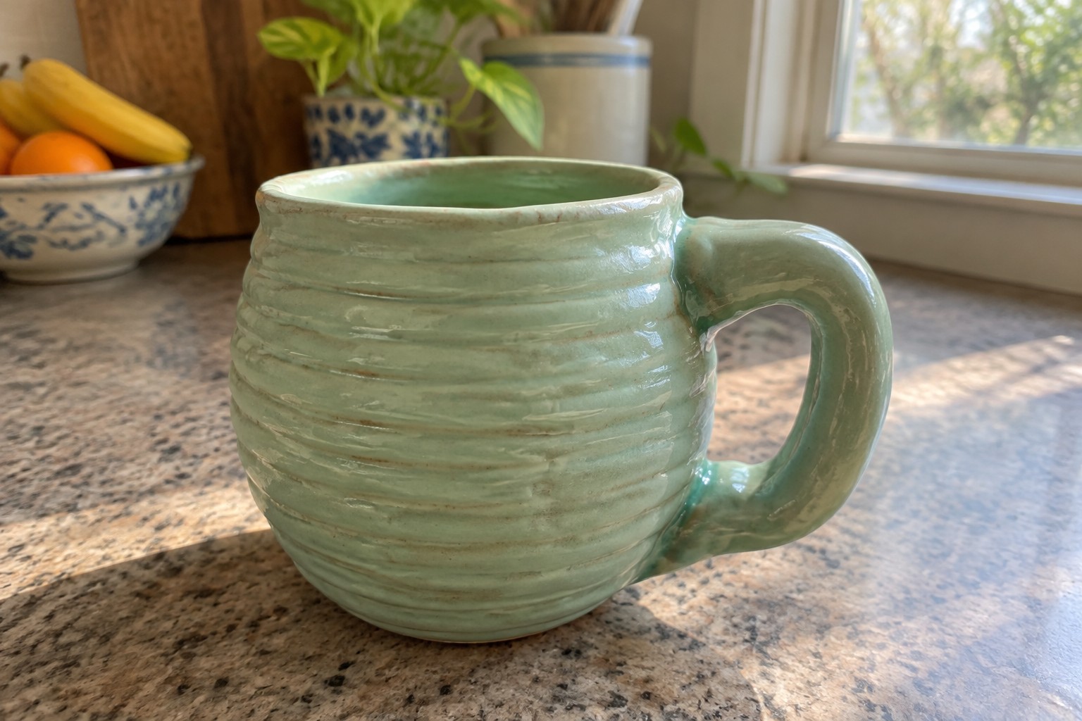 Light green ridged ceramic mug with handle on speckled kitchen countertop