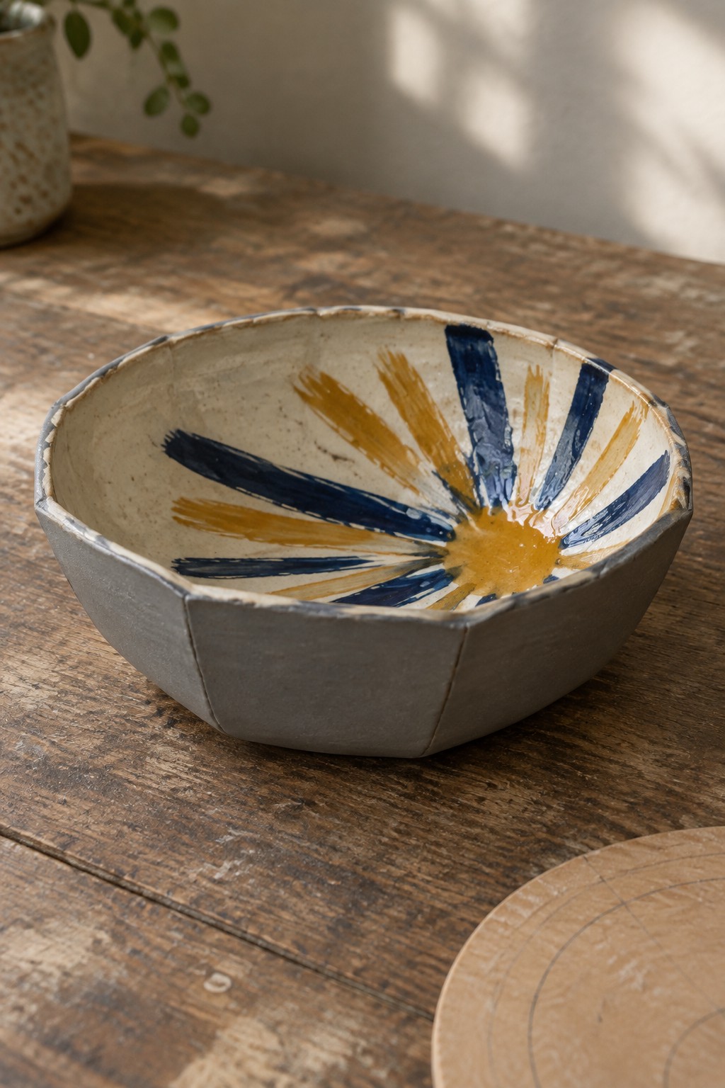 Ceramic bowl with blue and yellow sunburst pattern on rustic wooden table
