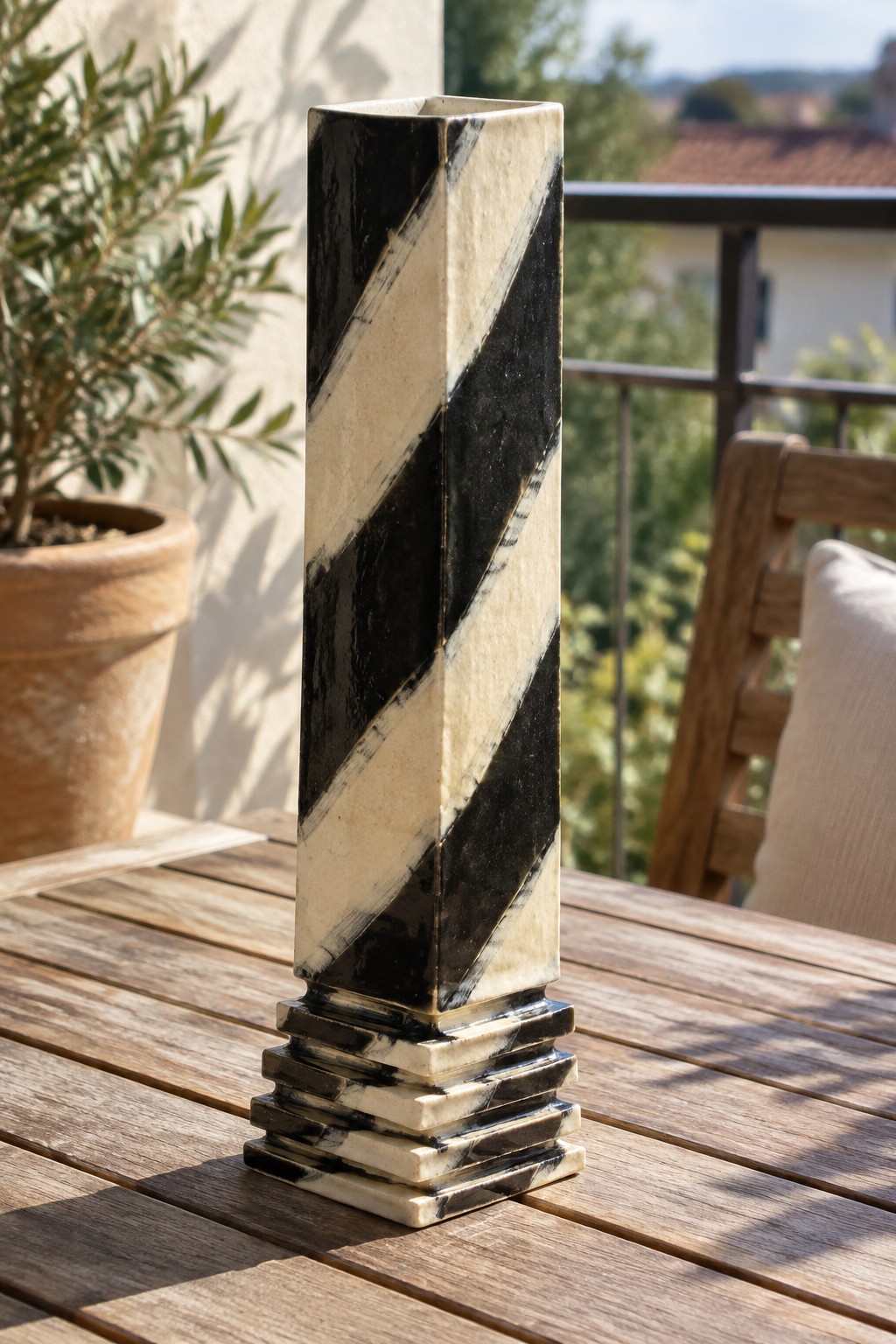 Tall black and white striped ceramic vase on wooden patio table