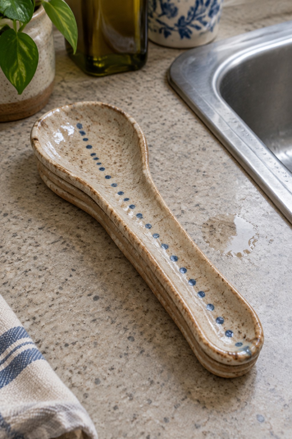 Stacked speckled ceramic spoons with blue dots on granite kitchen counter