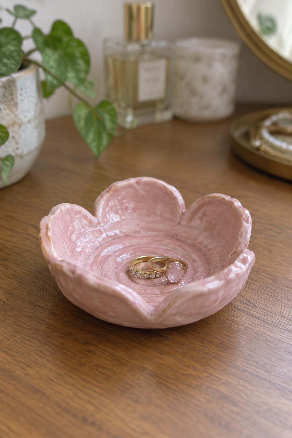 Pink flower-shaped ceramic bowl with two gold rings on wooden table