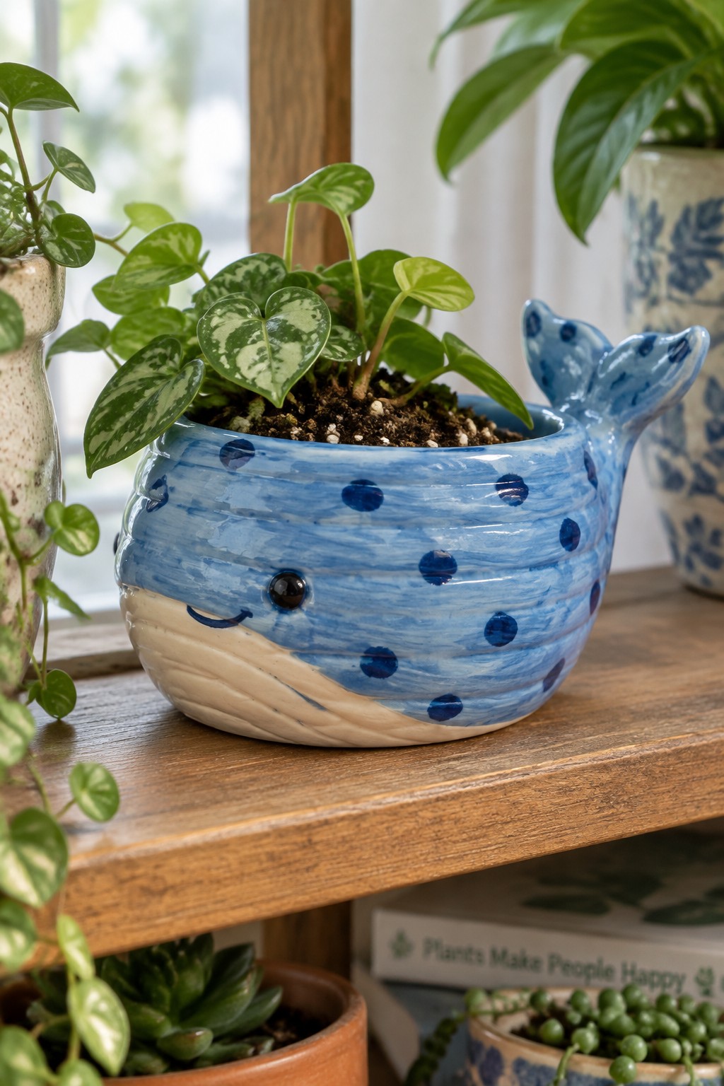 Blue whale ceramic planter with polka dots, smiling face, and leafy plant on shelf