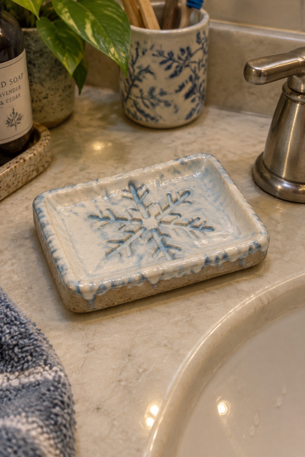 Blue and white snowflake soap dish on marble bathroom sink counter
