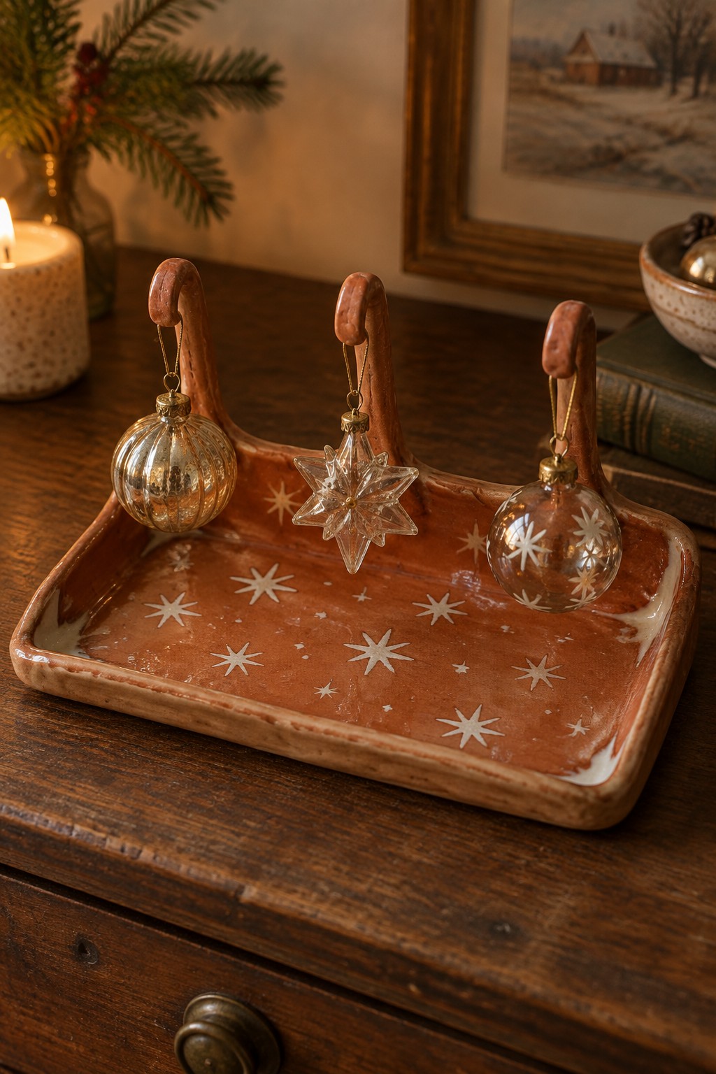 Rustic terracotta tray with white stars holding three glass Christmas ornaments