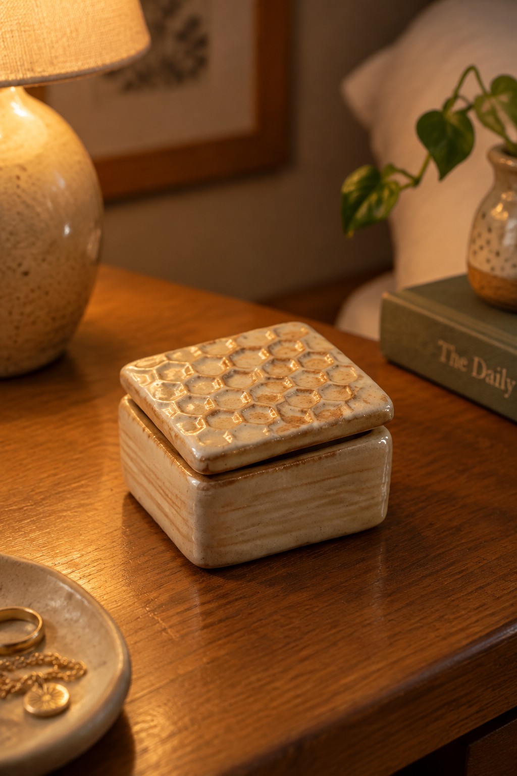 Ceramic box with honeycomb lid on wooden table beside lamp and book