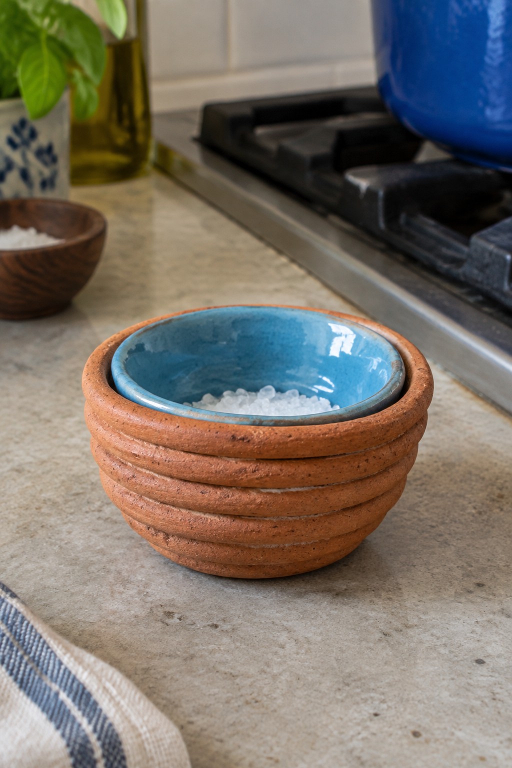 Blue ceramic bowl nested in ribbed terracotta bowl with coarse salt on counter