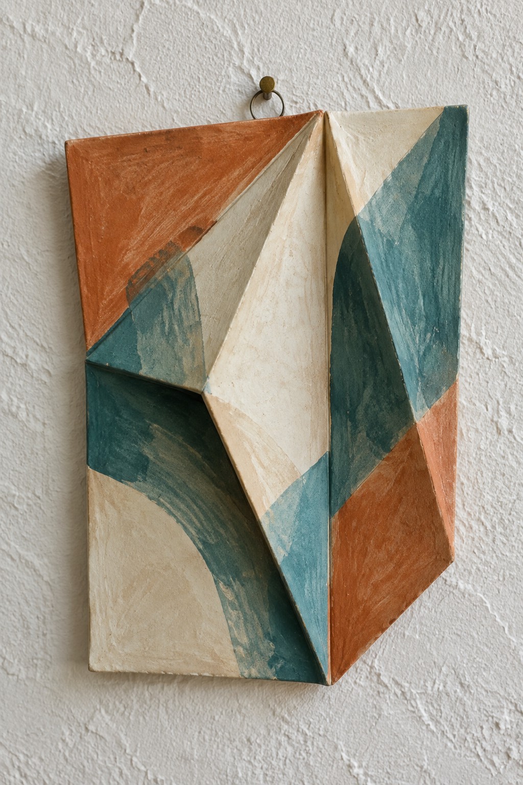 Geometric abstract wall relief with orange, teal, beige, and cream angular folds.