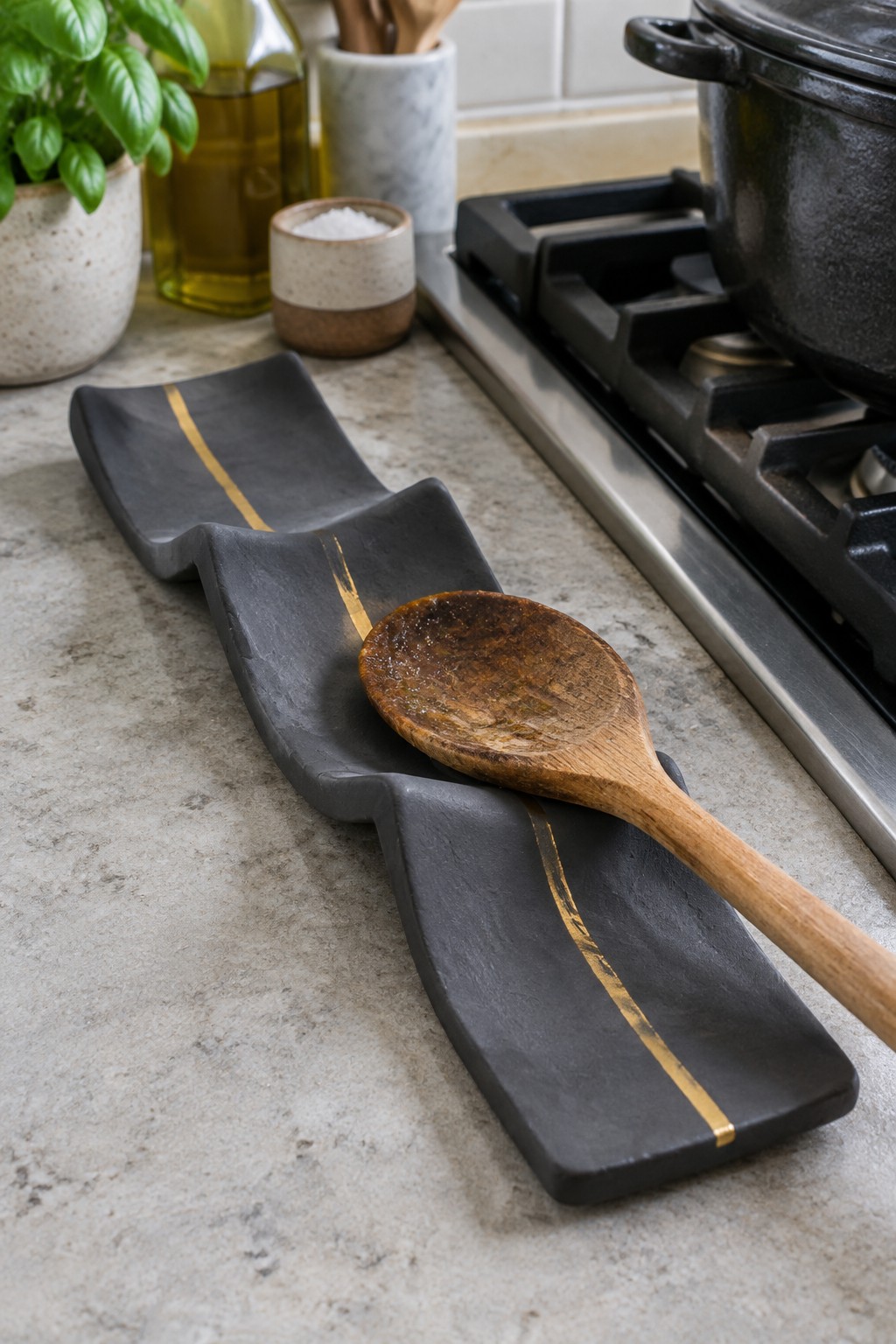 Wooden spoon on black wavy tray with gold stripes on kitchen counter