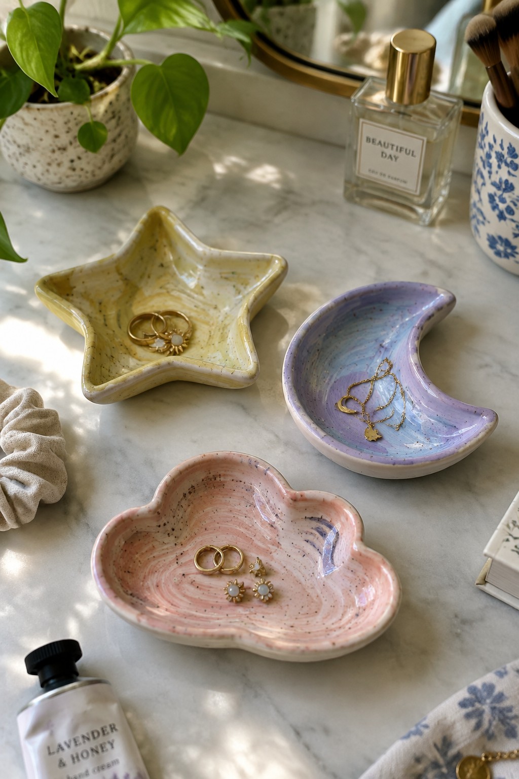 Pastel ceramic star, moon, and cloud dishes holding gold jewelry on marble vanity