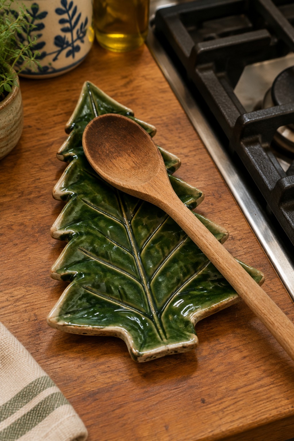 Green ceramic leaf spoon rest with wooden spoon on wooden kitchen counter