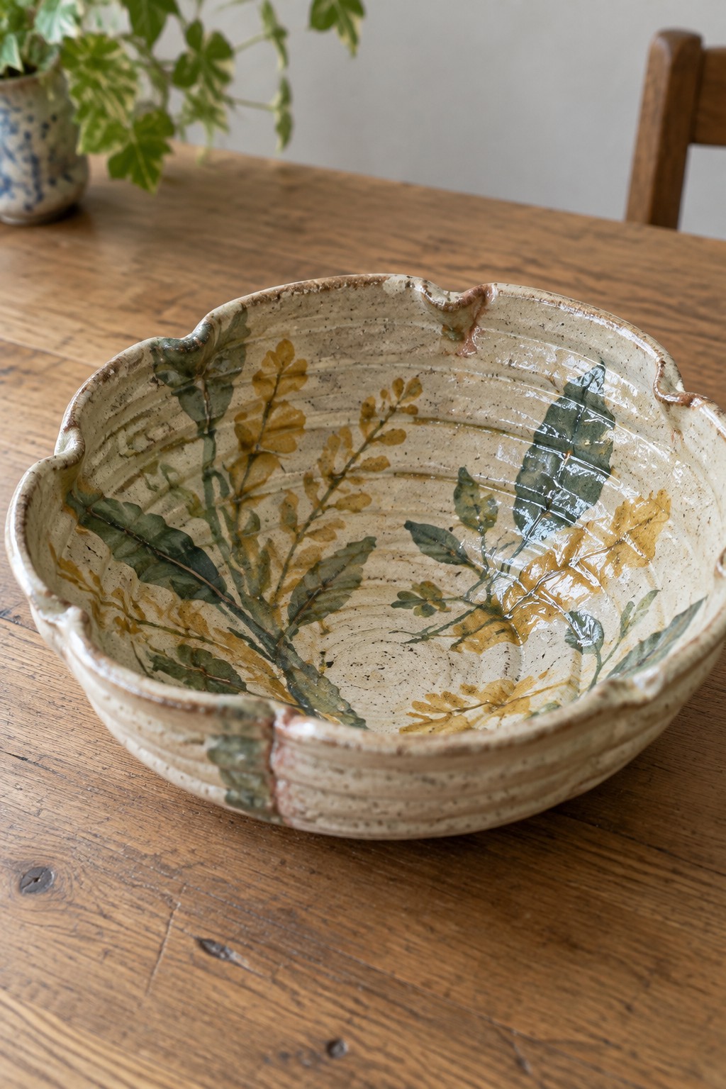 Ceramic bowl with green and yellow leaf designs on wooden table