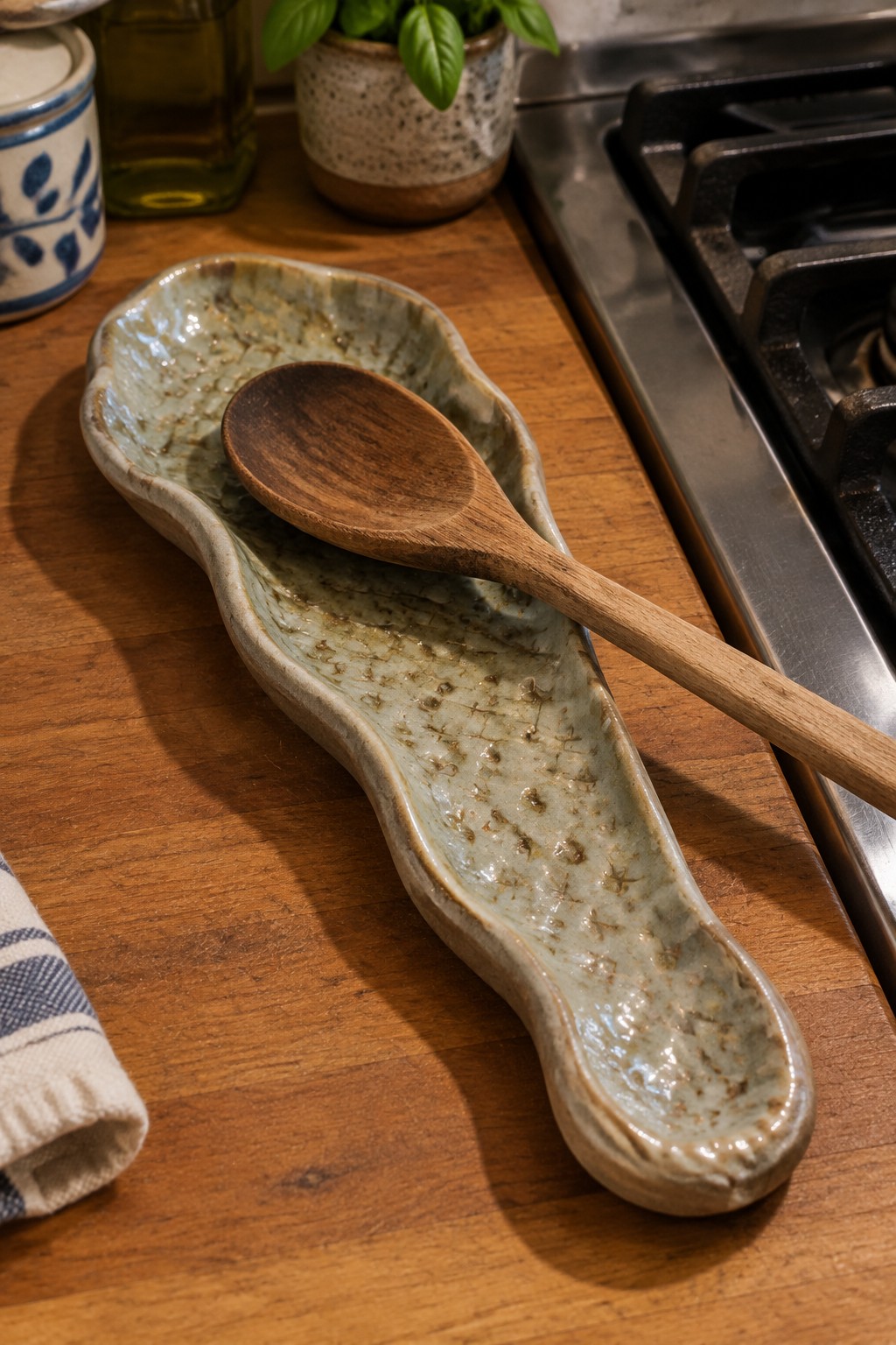 Wooden spoon resting in long ceramic dish on wooden kitchen counter