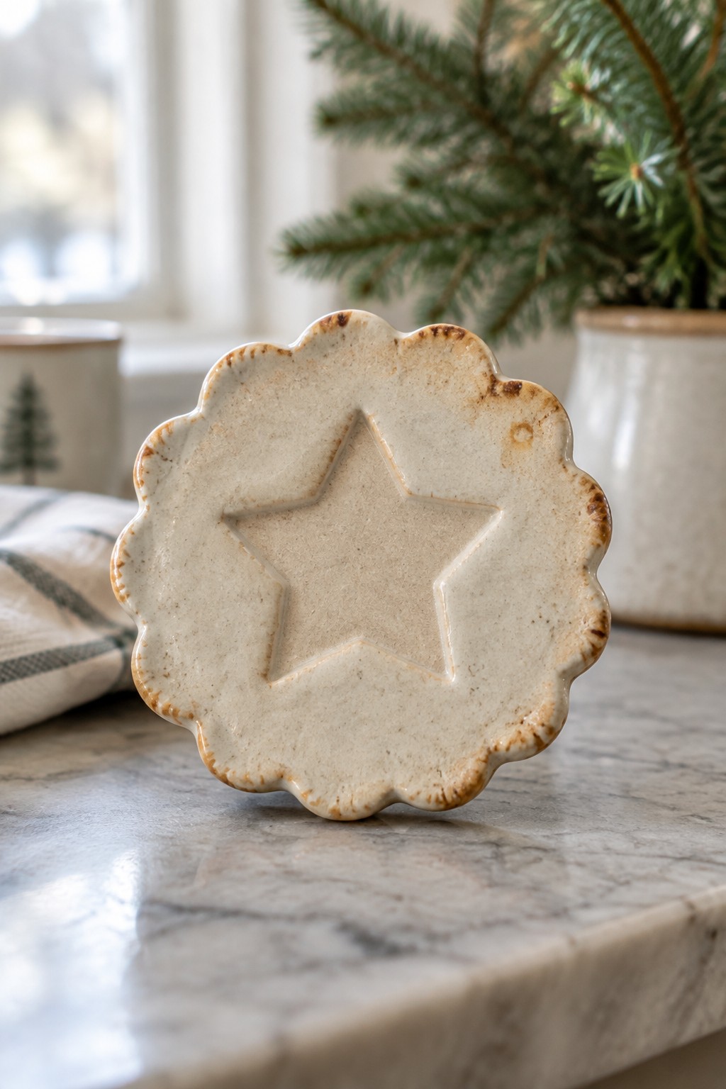 Cream ceramic star dish with scalloped edges on marble countertop