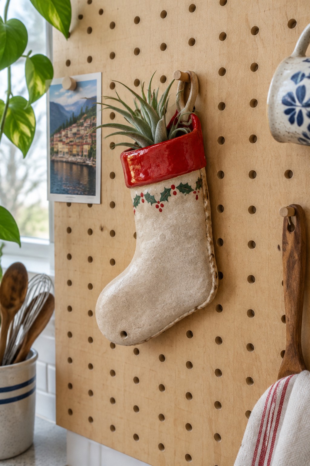 Ceramic Christmas stocking with red cuff holding air plant on wooden pegboard