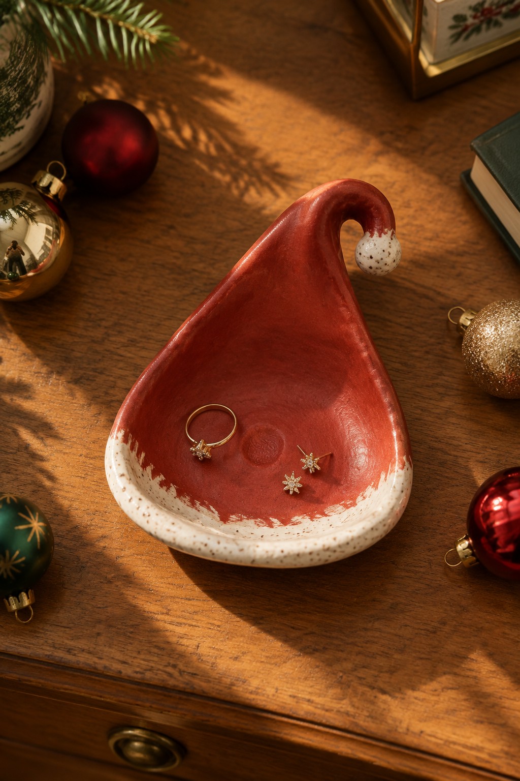 Red Santa hat ceramic dish with gold star jewelry on wooden table with ornaments