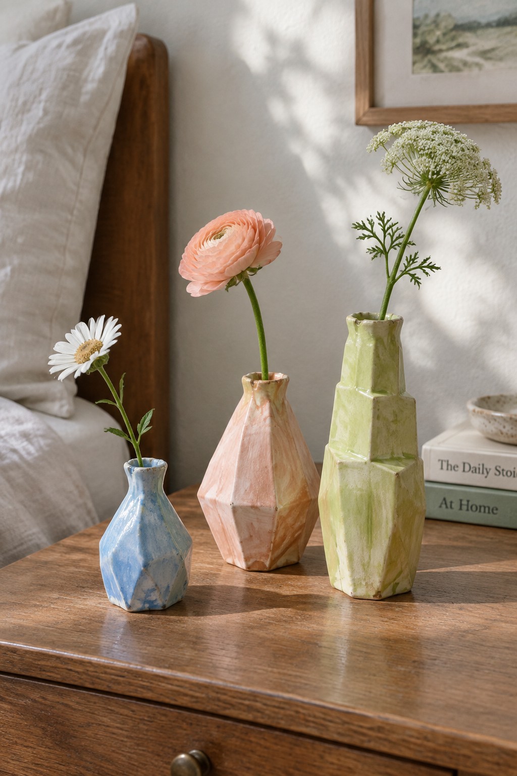 Three faceted ceramic vases with flowers on a wooden bedside table