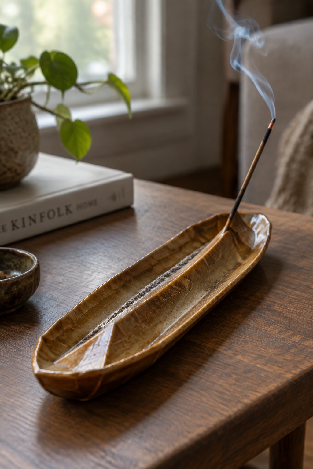 Burning incense in a long brown crackled ceramic holder on wooden table