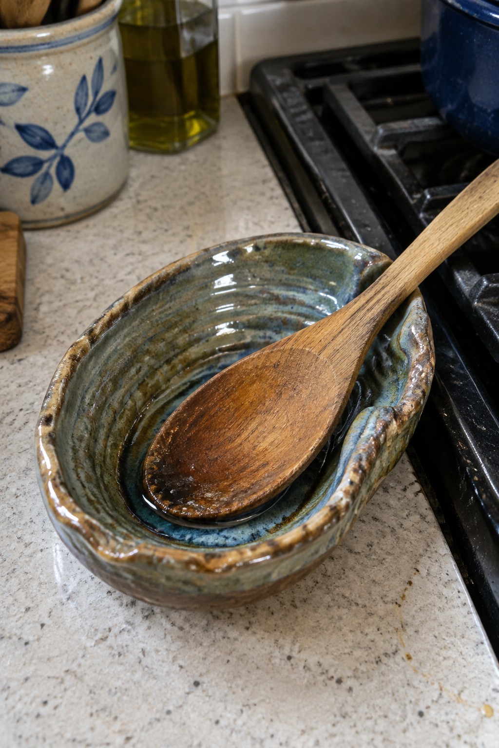 Ceramic bowl with wooden spoon on kitchen countertop near stove