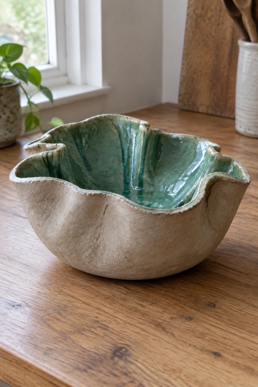 Wavy-edged ceramic bowl with beige texture and glossy green interior on wooden table