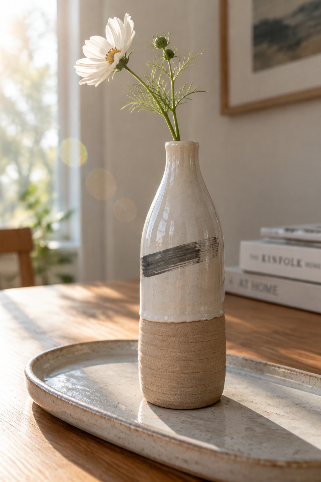 Two-toned ceramic vase with white flower and black stripe on tray