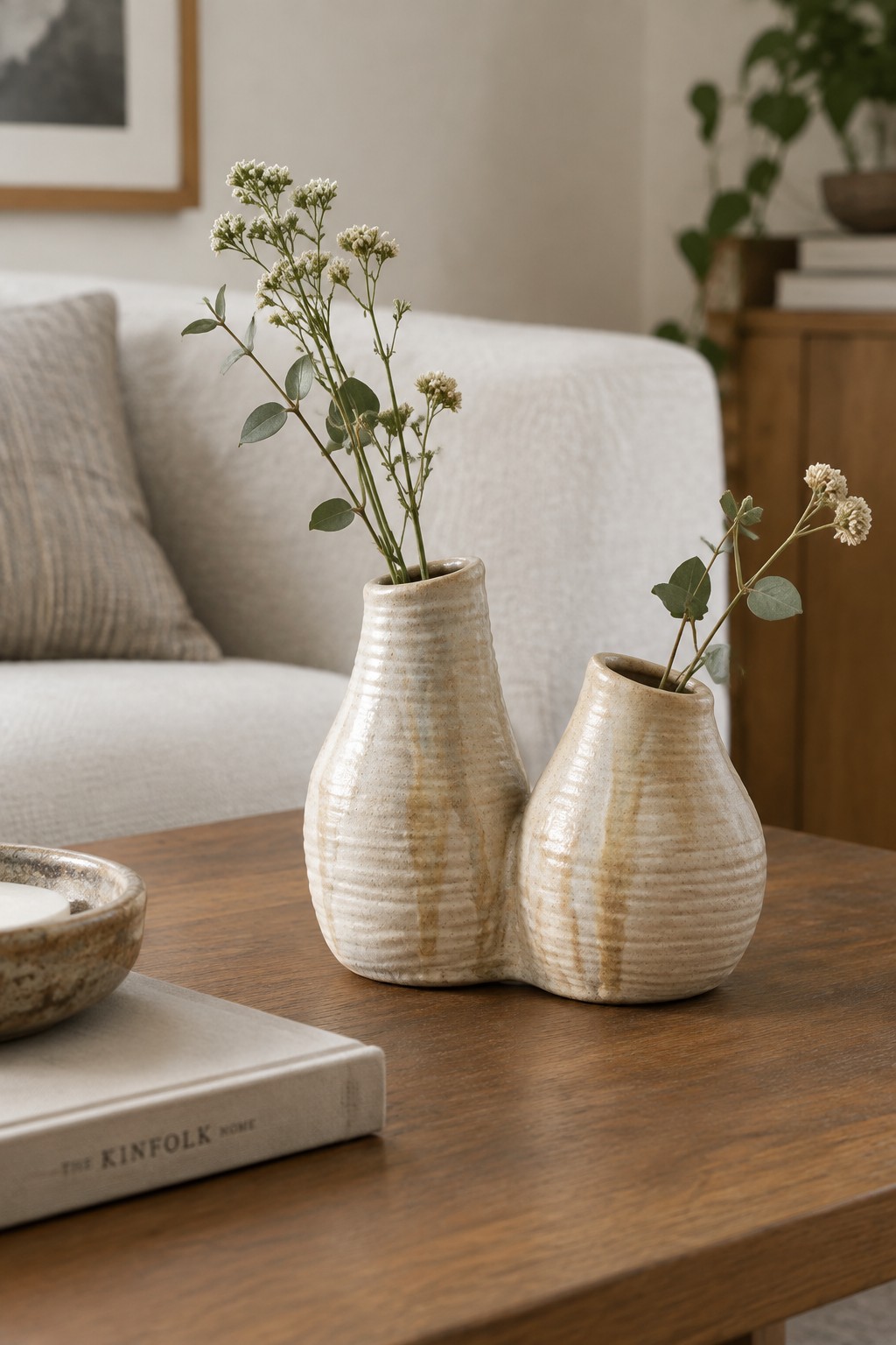 Two connected ceramic vases with wildflowers on a wooden coffee table
