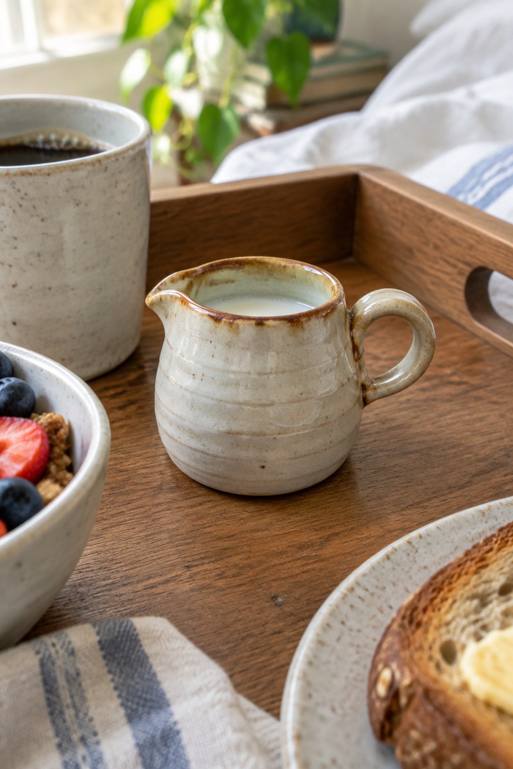 Rustic wooden tray with coffee mug, milk pitcher, berry bowl, and toast