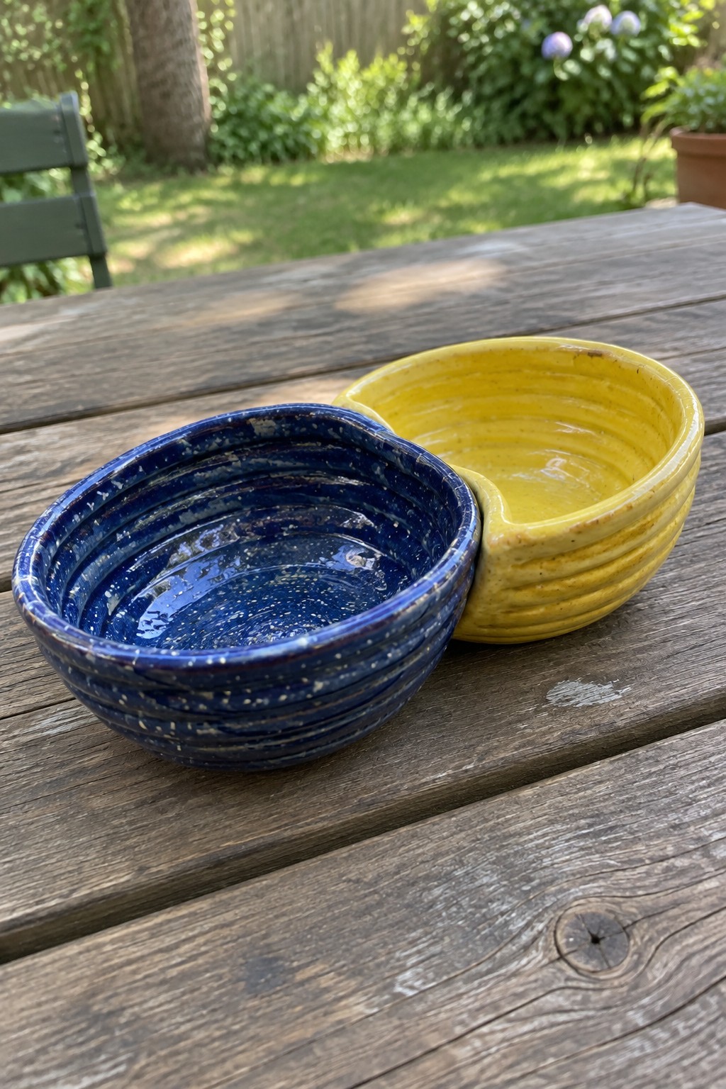 Blue and yellow ridged ceramic bowls on wooden garden table outdoors