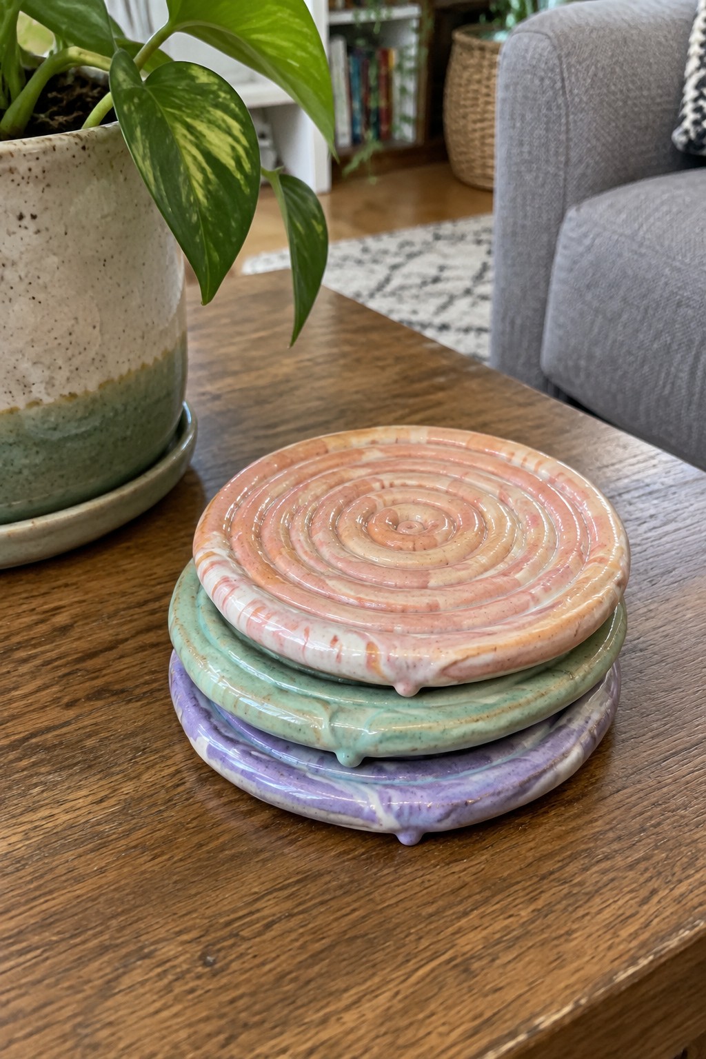 Stack of pink, green, purple swirled ceramic coasters on wooden table